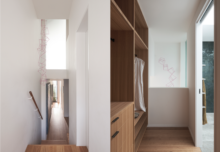 Wide angle of modern hallway and entrace area at Ahron Best featured project. Featuring woodgrain floors and cabinets against white walls.