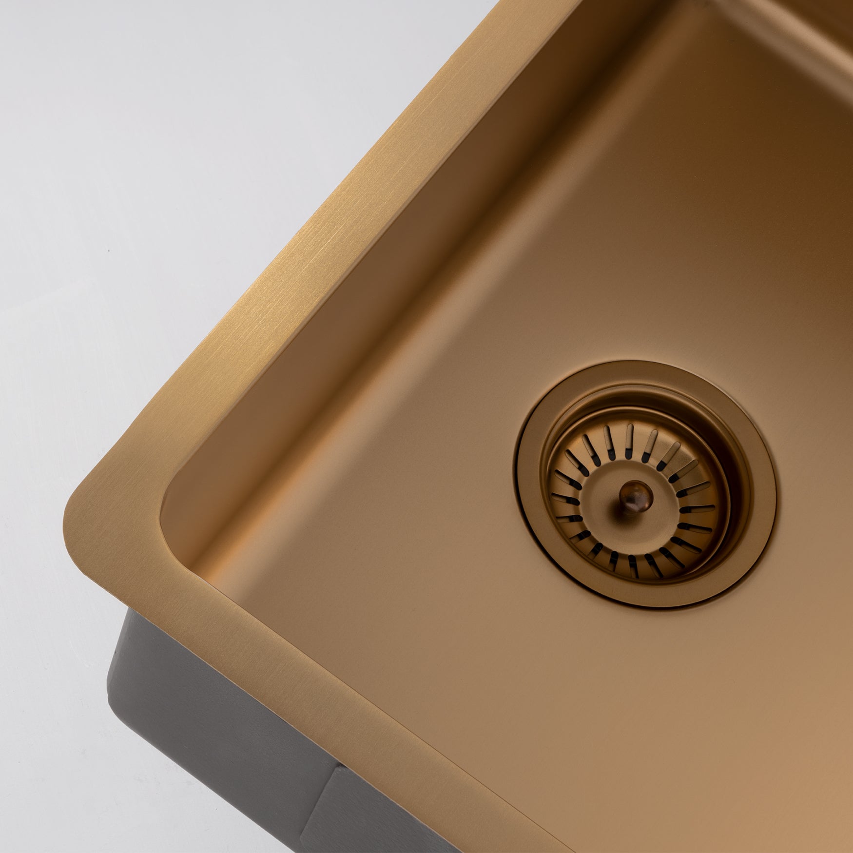 Close-up still life image of a Titan large bowl brass sink against a gray background, highlighting the elegant design of the brass sink.