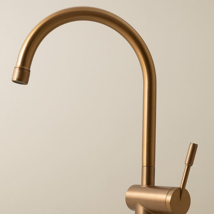 Close-up of a sleek Titan brass gooseneck kitchen mixer tap against a neutral background, highlighting the elegant design of the kitchen tap.