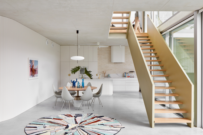 Modern interior of the Owston Hill featured project by Meaghan White Architect, showcasing a minimalist dining area, open staircase, and kitchen space, with Titan products integrated into the design.