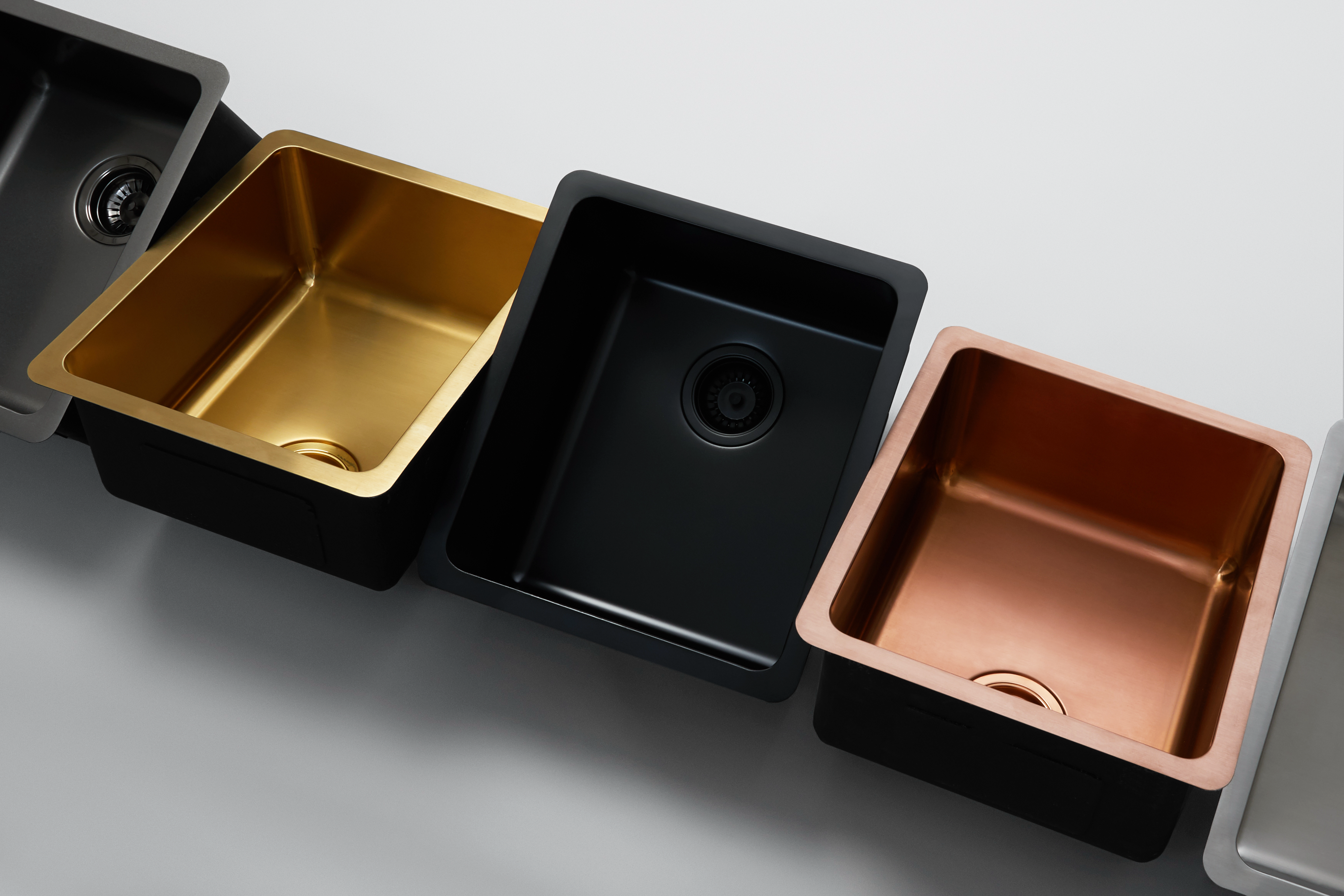 Close up image of five Titan medium bowl sinks in different colour including stainless steel, rose gold, matte black, brass and gunmetal